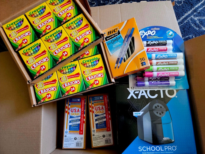 An open Amazon box filled with school supplies for a teacher.