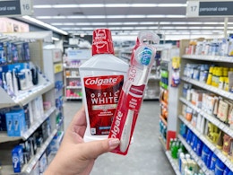 hand holding colgate mouthwash and toothbrush in walgreens
