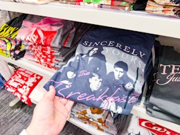 hand grabbing a women's graphic tee off a target shelf