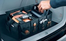 a hand taking an item out of a trunk organizer in a car