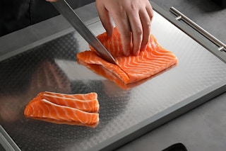 stainless steel cutting board being used to cut fish