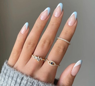 A hand modeling blue and white french tip nails