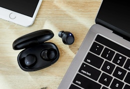 black onn earbuds next to a Macbook