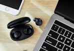 black onn earbuds next to a Macbook