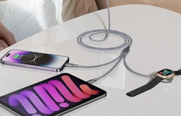 a charging cable charging three devices on a table