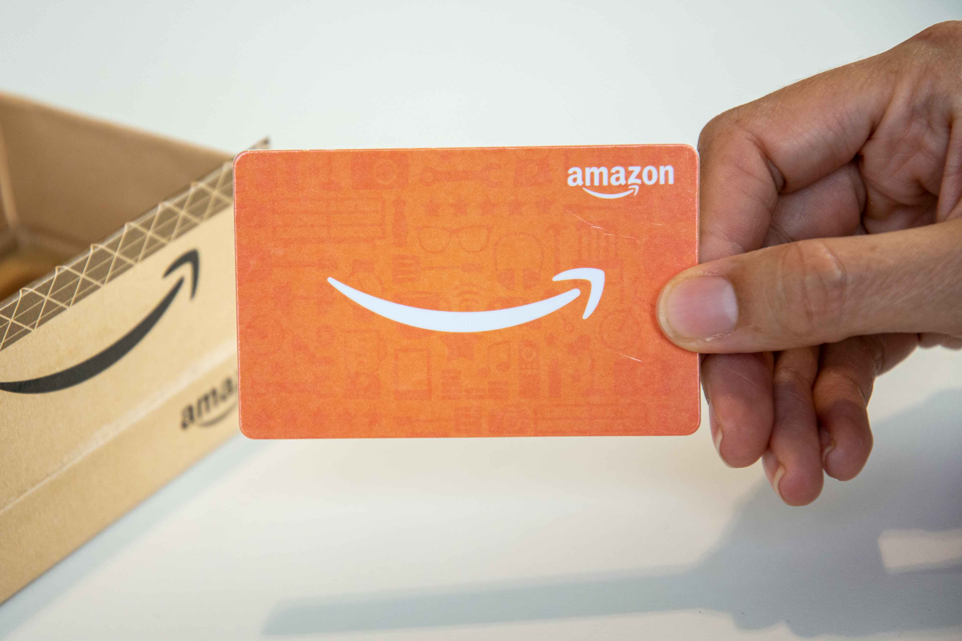 earn free gift cards - A person holding an Amazon gift card.
