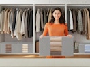 a person in a closet with clothes in a storage bag 