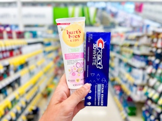 hand holding two tubes of crest and burt's bees toothpaste