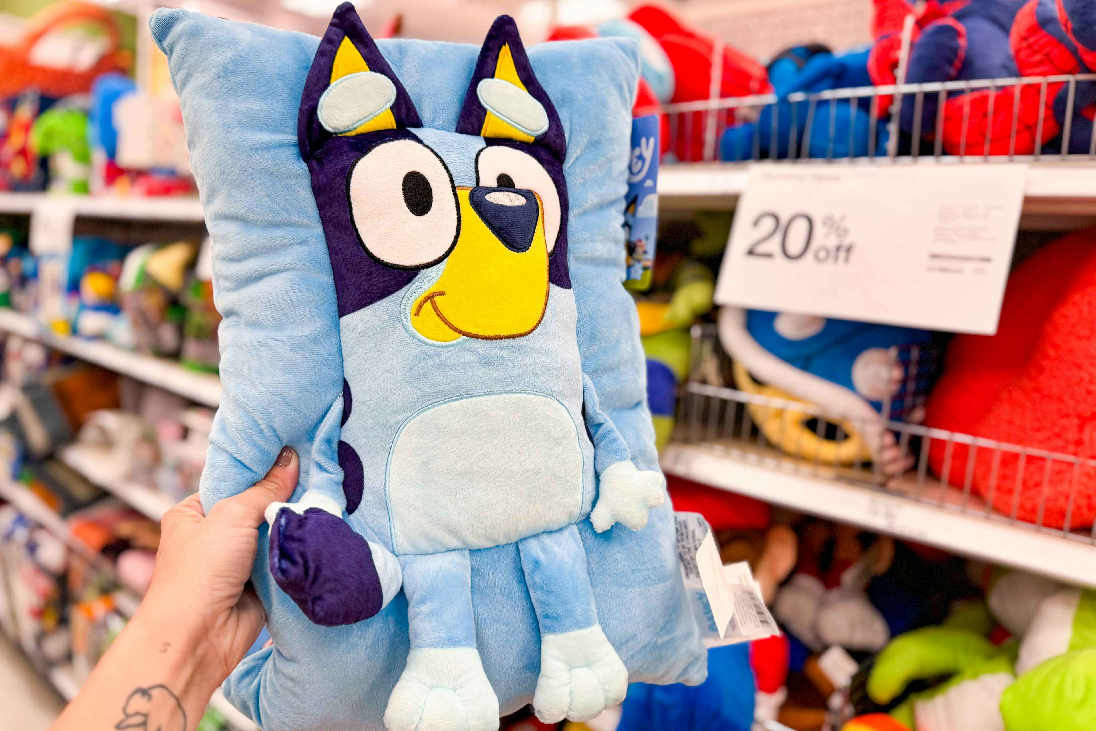Targey Bluey Pillow Buddy, held up in front of other plush character pillows at Target