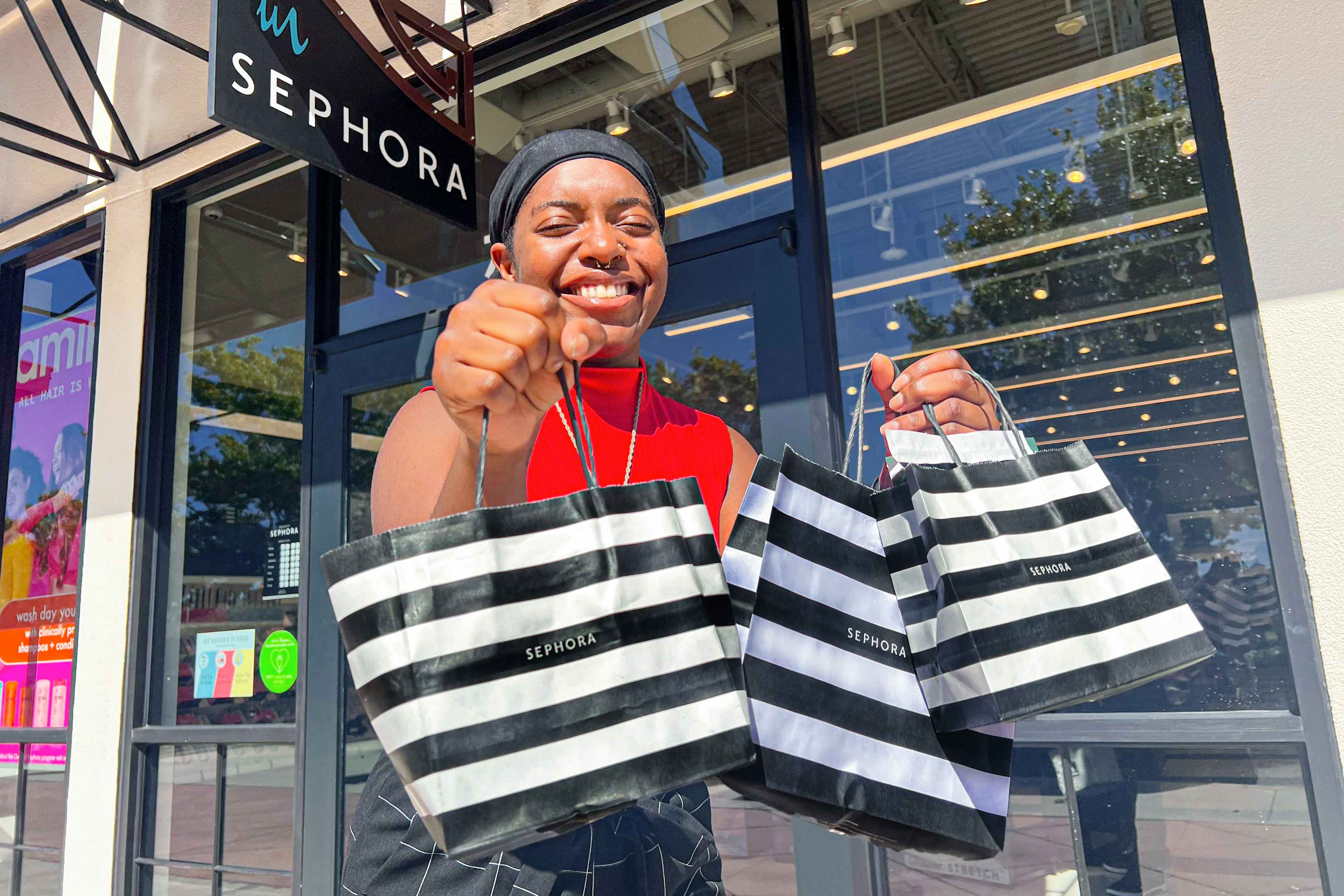 someone holding a bunch of Sephora shopping bags outside of the store