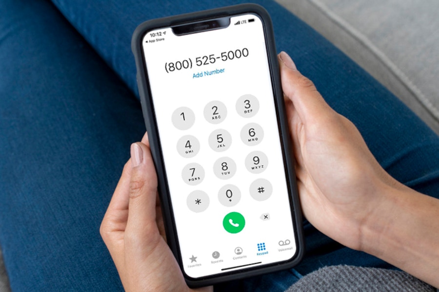 A woman holding her phone, dialing a customer service number to ask about returns.