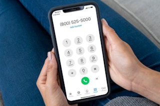 A woman holding her phone, dialing a customer service number to ask about returns.