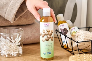 a woman holding a bottle of now solutions castor oil