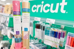 hand holding 2 cricut vinyl rolls in front of target shelf