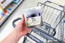 person holding an olay moisturizer over a walgreens cart