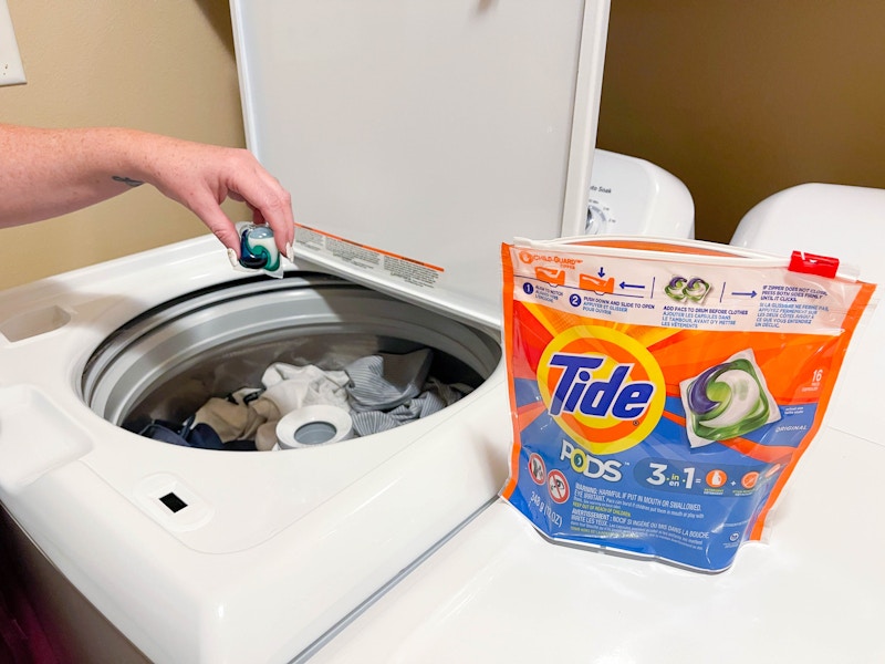 putting a tide pod in washer filled with clothes