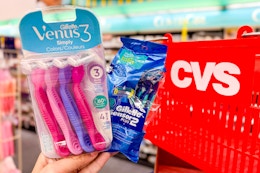 hand holding gillette and venus disposable razors in front of cvs basket
