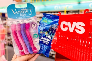 hand holding two Gillette and Venus razors next to CVS shopping basket