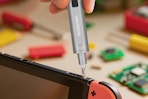 person using mini screwdriver on gaming device