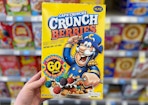 hand holding a box of cap'n captain crunch cereal