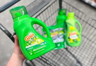 hand holding gain laundry detergent with more gain laundry care in cart