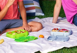 green and gray Bentgo lunch boxes on a blanket with kids