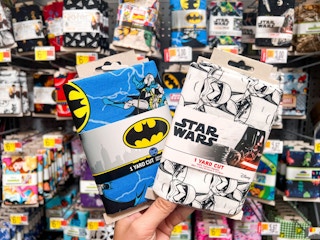 Hand holding Batman & Star Wars printed quilting fabric
