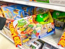 hand grabbing a hot wheels city t-rex set off a target shelf