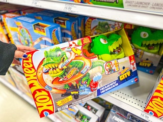 hand grabbing a hot wheels city t-rex set off a target shelf