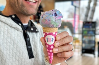 a person holding a Baskin Robbins cone with a scoop of ice cream.