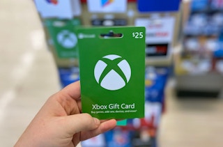 a hand holding a green Xbox gift card