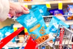 person placing a bag of pretzels in a cart