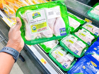 Hand holding Perdue Harvestland Chicken Drumsticks at Walmart