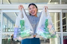 a woman holding up dollar tree bags outside store