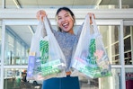 a woman holding up dollar tree bags outside store