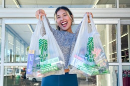 a woman holding up dollar tree bags outside store