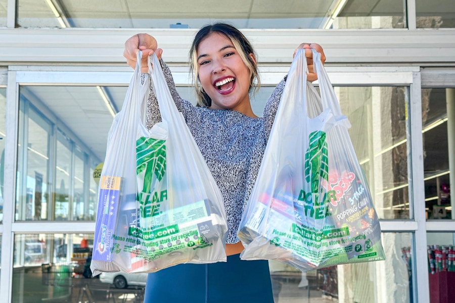 a woman holding up dollar tree bags outside store