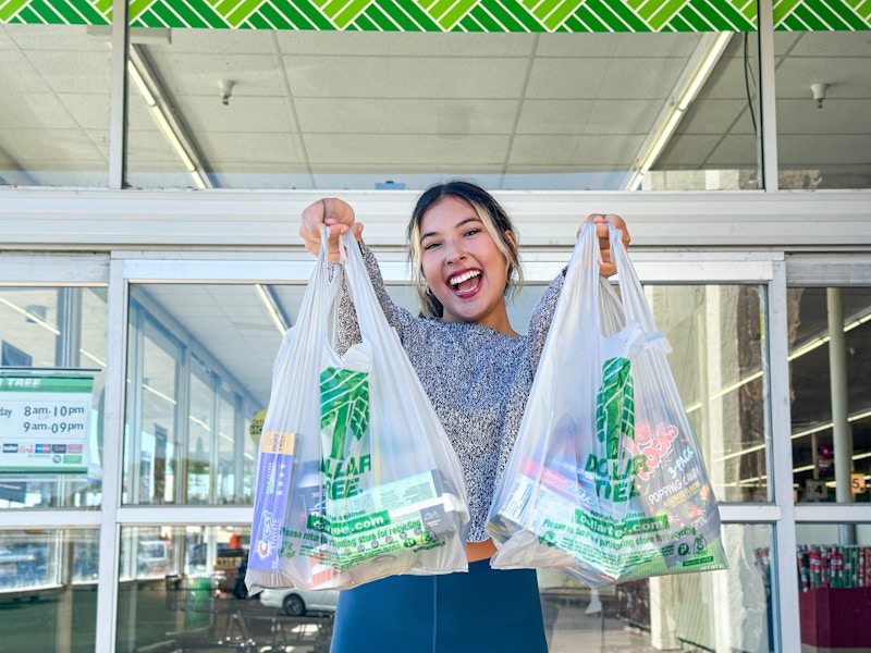 a woman holding up dollar tree bags outside store