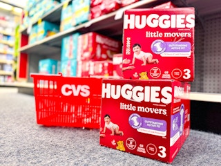 two stacked boxes of huggies diapers next to cvs shopping basket
