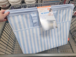 hand holding a set of 2 flexible blue striped laundry baskets in a cart