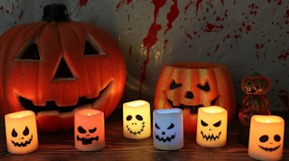 Colorful flameless candles on a table with pumpkins