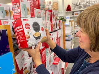 A woman looking at a small Waffle Iron at Kohls