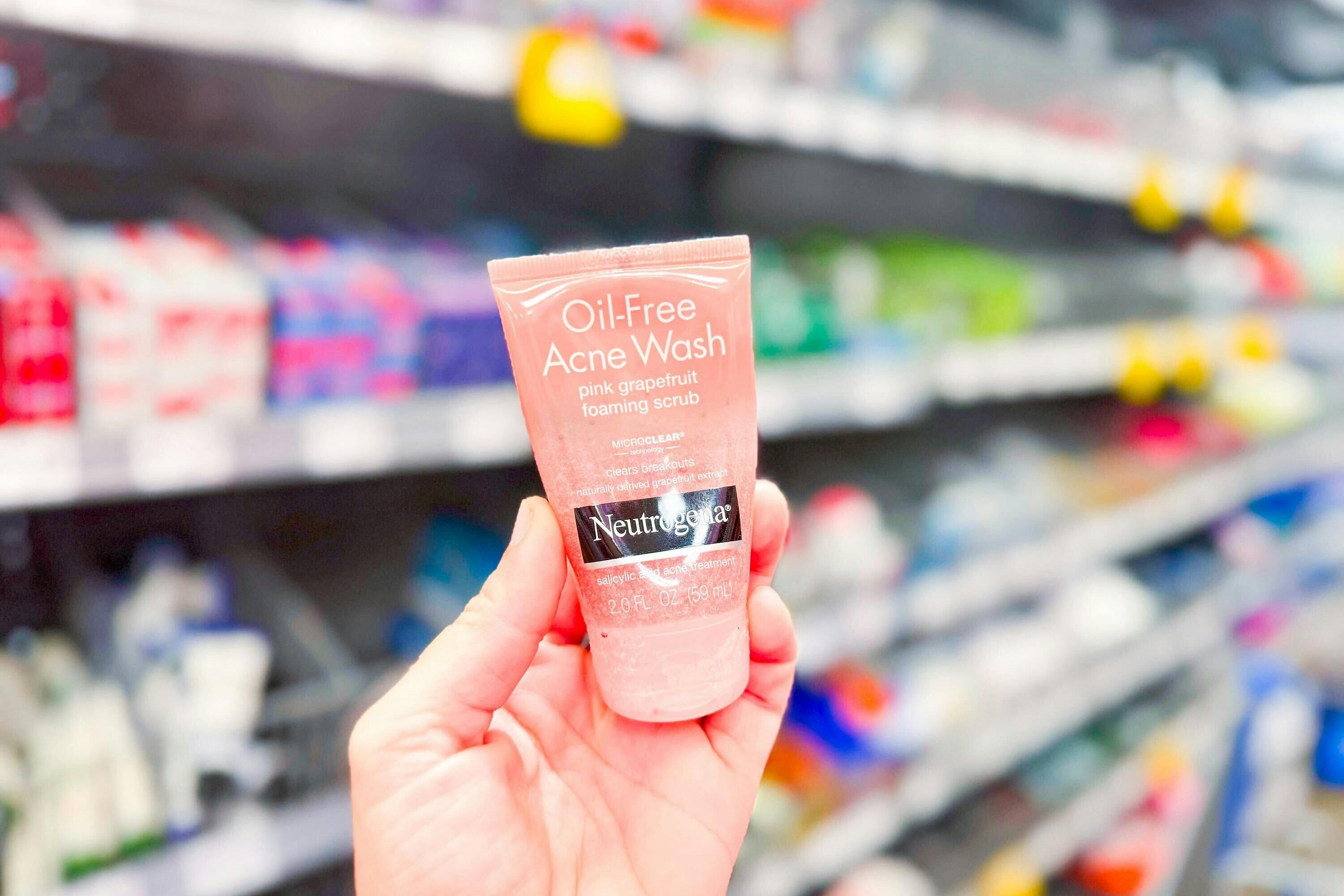 hand holding a bottle of neutrogena acne face wash in walmart aisle