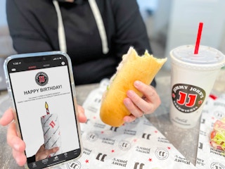 cellphone with birthday app and woman holding sandwich 