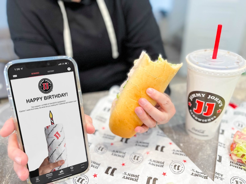 cellphone with birthday app and woman holding sandwich