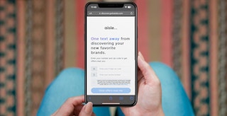 Someone holding a phone showing the Aisle website sign up page