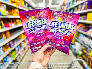 hand holding two life savers gummies over walmart cart