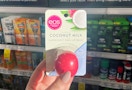 A hand holding Eos lip balm in a store aisle.