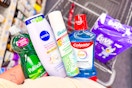 person holding palmolive, nivea, batiste, and colgate products over a cart with luvs diapers in it