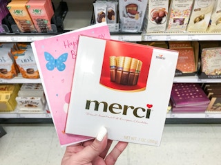 hand holding merci chocolate box and a greeting card at target